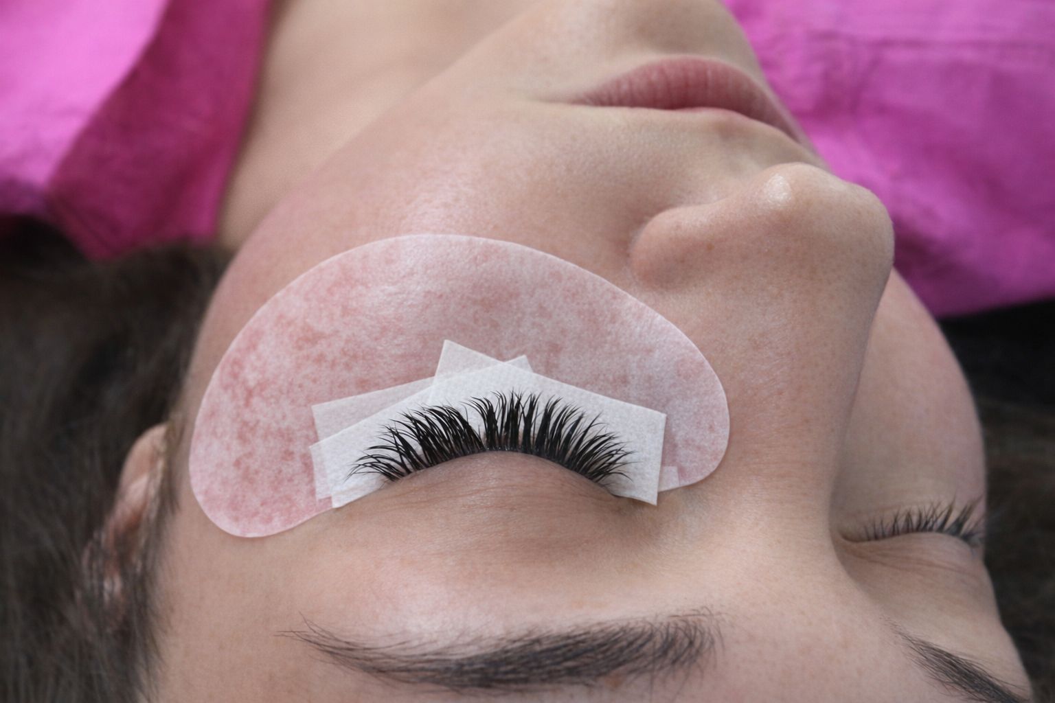 Närbild på fransförlängning med skyddande eye pads och tejp.